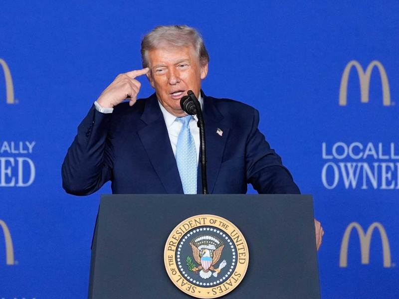 Donald Trump points at his temple while speaking at a McDonalds conference