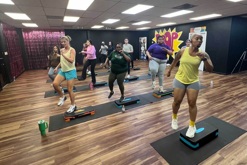 A room full of women exercise in rows