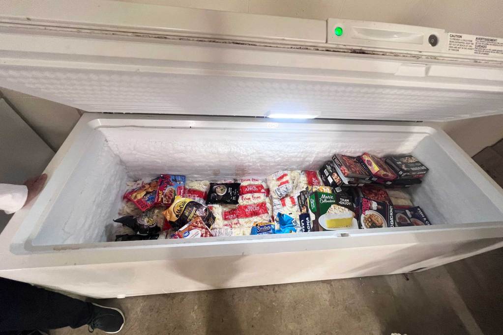 An open deep freezer filled with various frozen foods