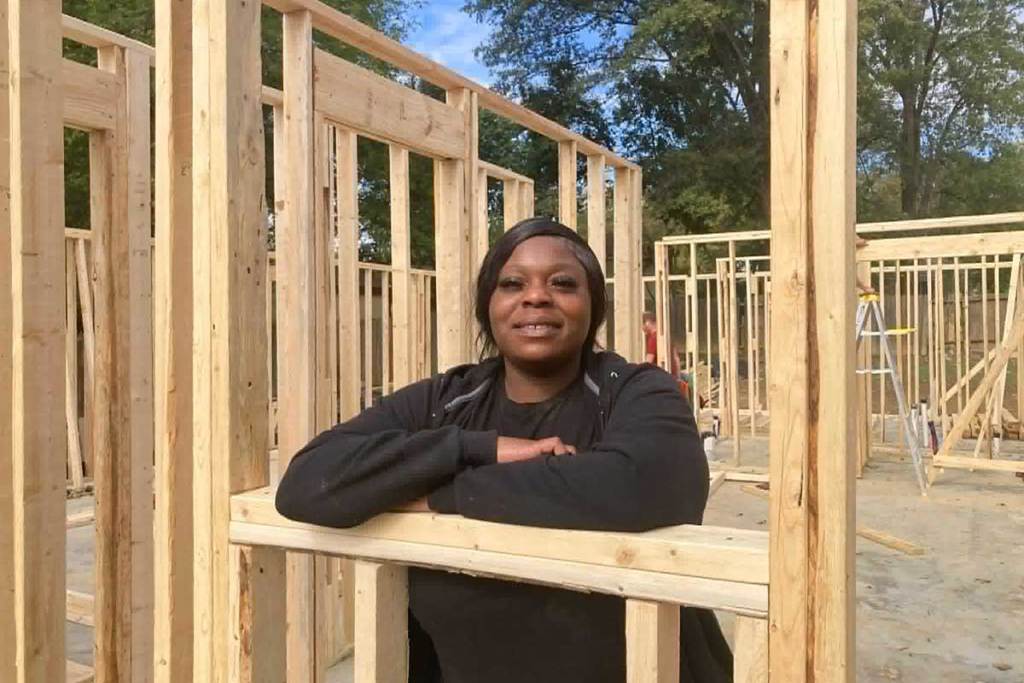 A woman stands inside the frame of a building