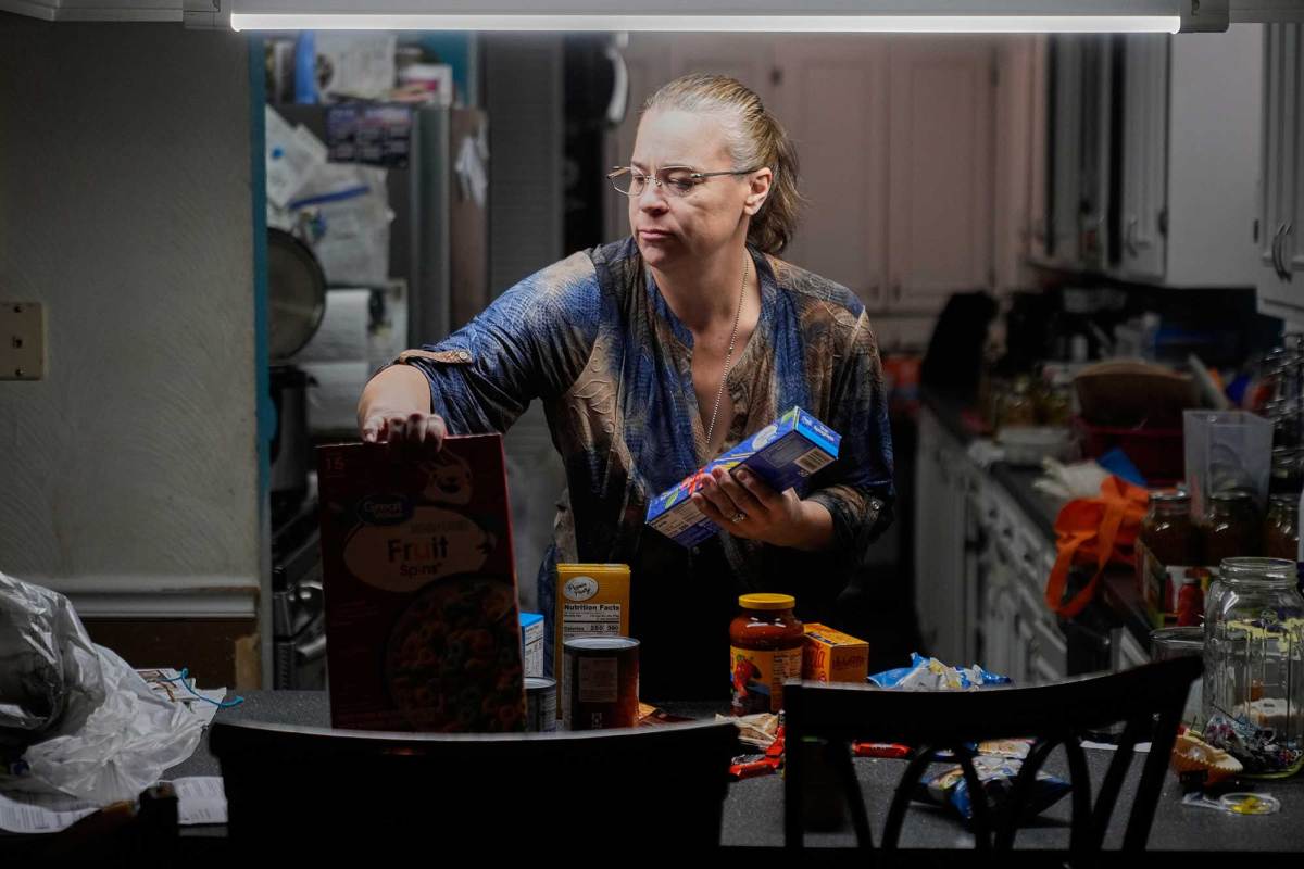 A woman sorts through groceries in her kitchen