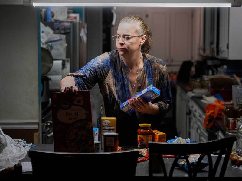 A woman sorts through groceries in her kitchen