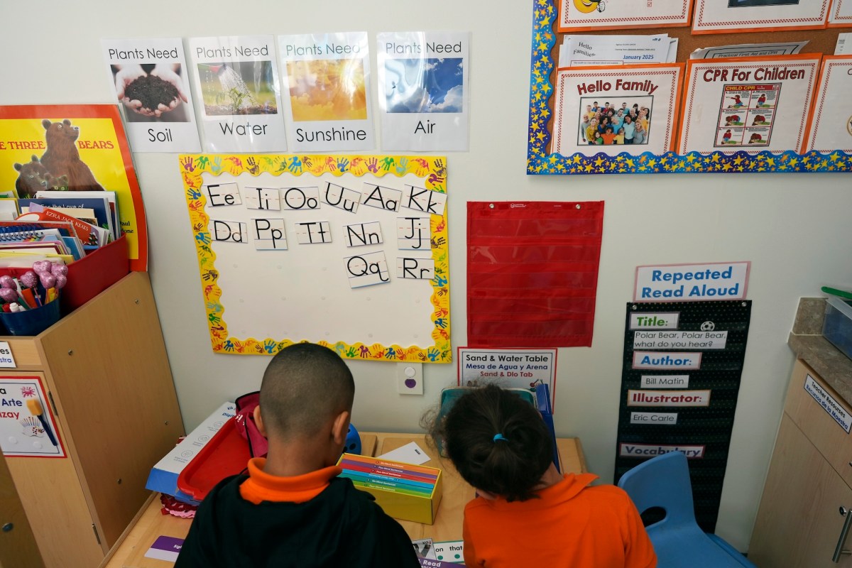 photo shows children from the back as they look at their ABCs on the wall