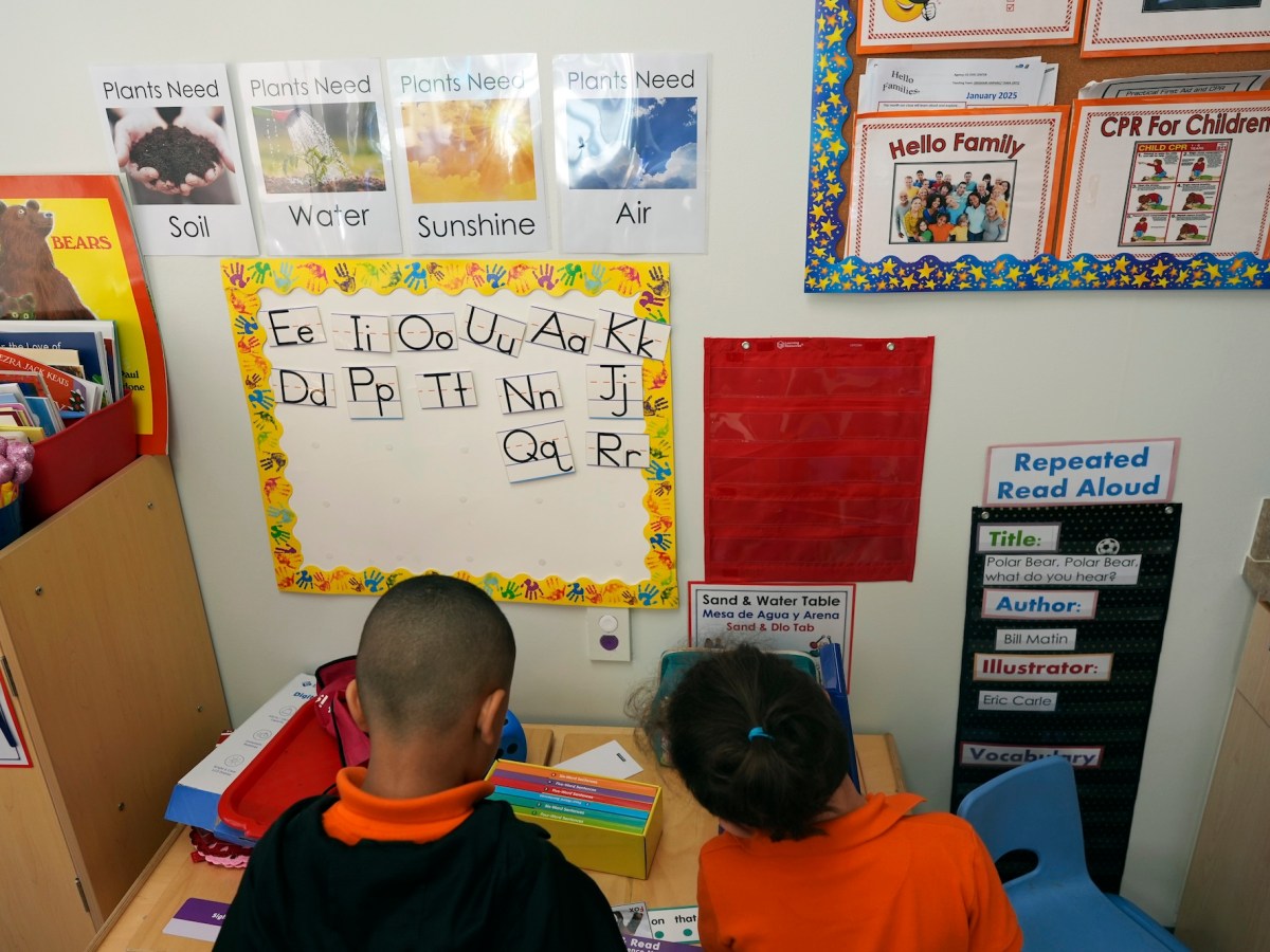 photo shows children from the back as they look at their ABCs on the wall