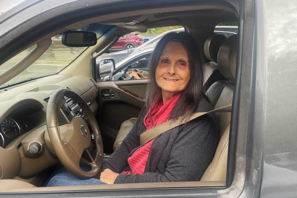 A woman sits in her vehicle outside of a church doing food donations