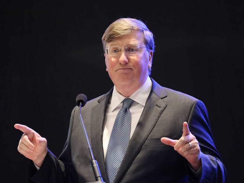 Tate Reeves speaks on stage, both hands up in a pointing gesture