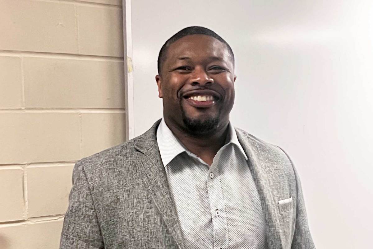 A man smiles in front of a whiteboard