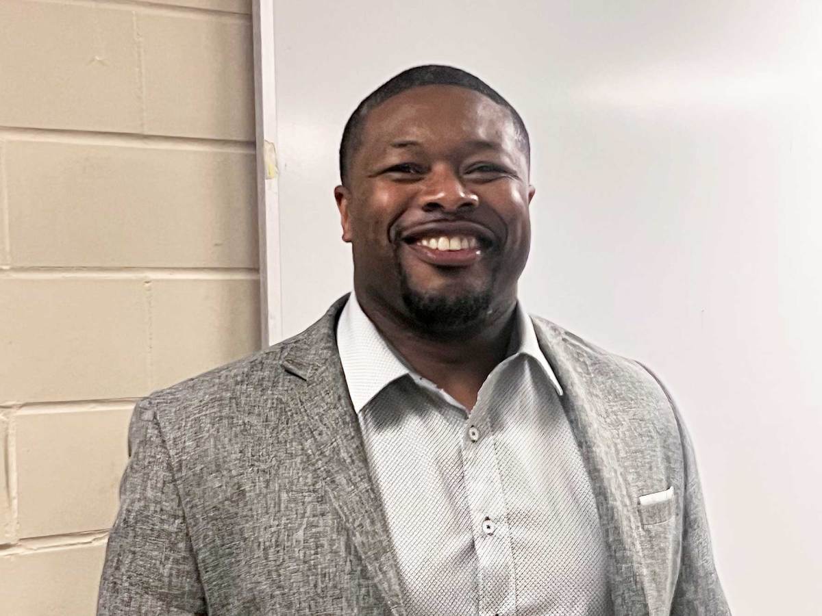 A man smiles in front of a whiteboard
