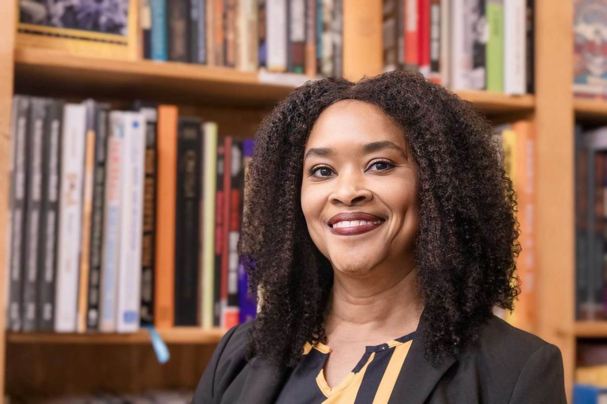 LaWanda Dickens smiles in front of a large bookcase filled with books