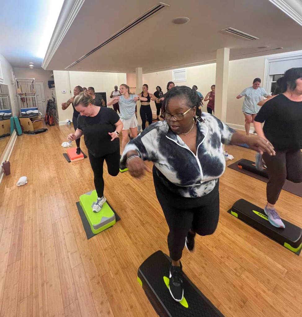 A room full of women do exercises on small platforms