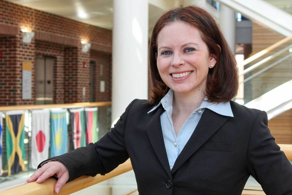 Lindsey Haynes-Maslow posed inside a white and brick building with flags visible in the background