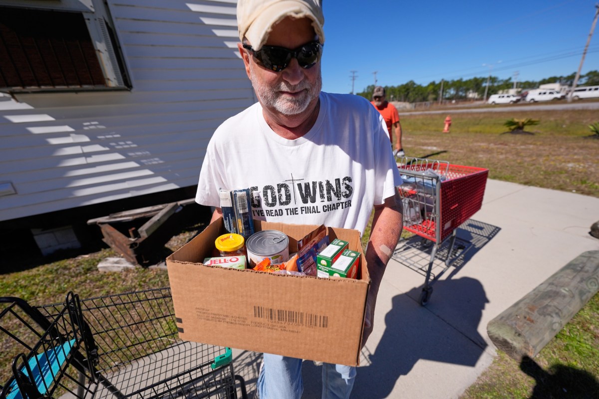 a man is carying a cardboard box full of food items