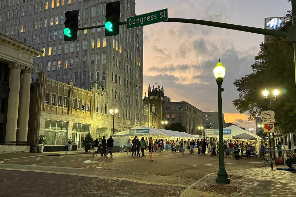Rows of vendor tents can be seen in the road in downtown Jackson at dusk