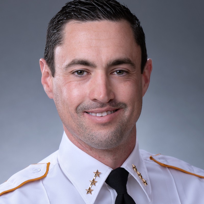 Official headshot of Josh Bromen, three stars visible on each lapel