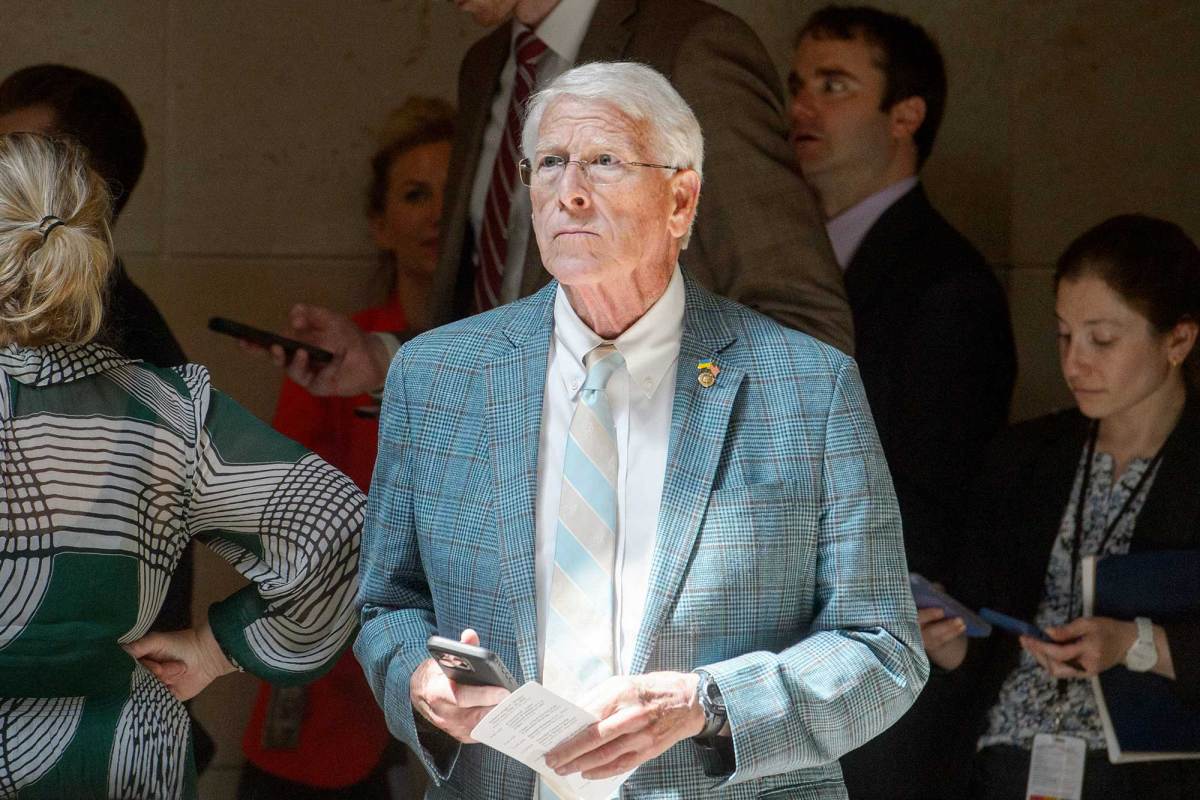 Roger Wicker standing inside in front of a crowd, holding his phone in one hand and a piece of paper in the other