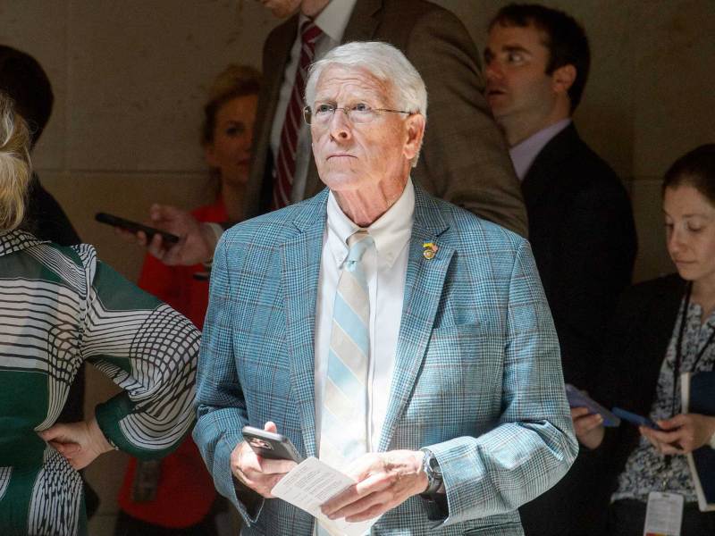 Roger Wicker standing inside in front of a crowd, holding his phone in one hand and a piece of paper in the other