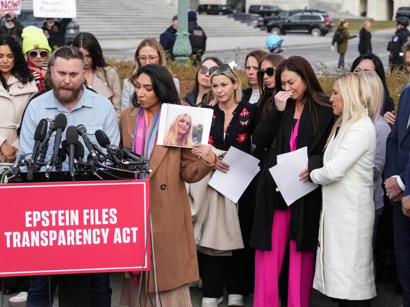 Sky Roberts speaks at a press conference as someone holds up a photo of his sister Virginia Giuffre beside him