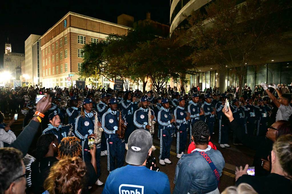 Jackson State University's Sonic Boom band marches through downtown Jackson at night as crowds watch on