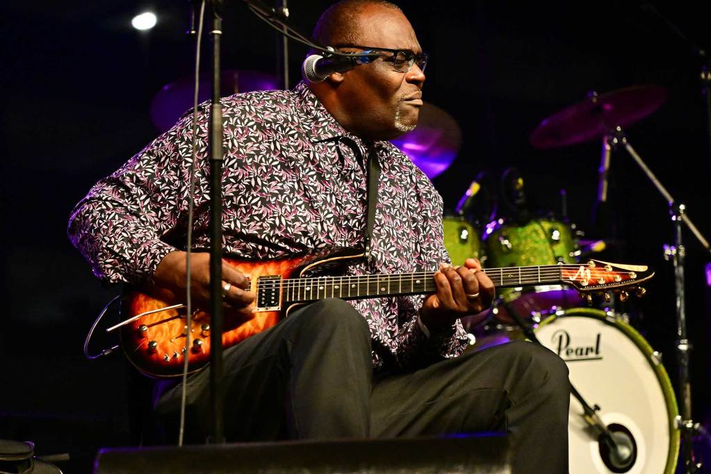 A man sits on stage and plays guitar