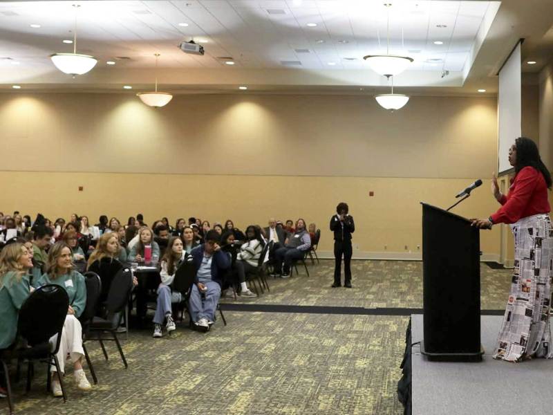 Torsheta Jackson standing on stage speaking to a packed audience