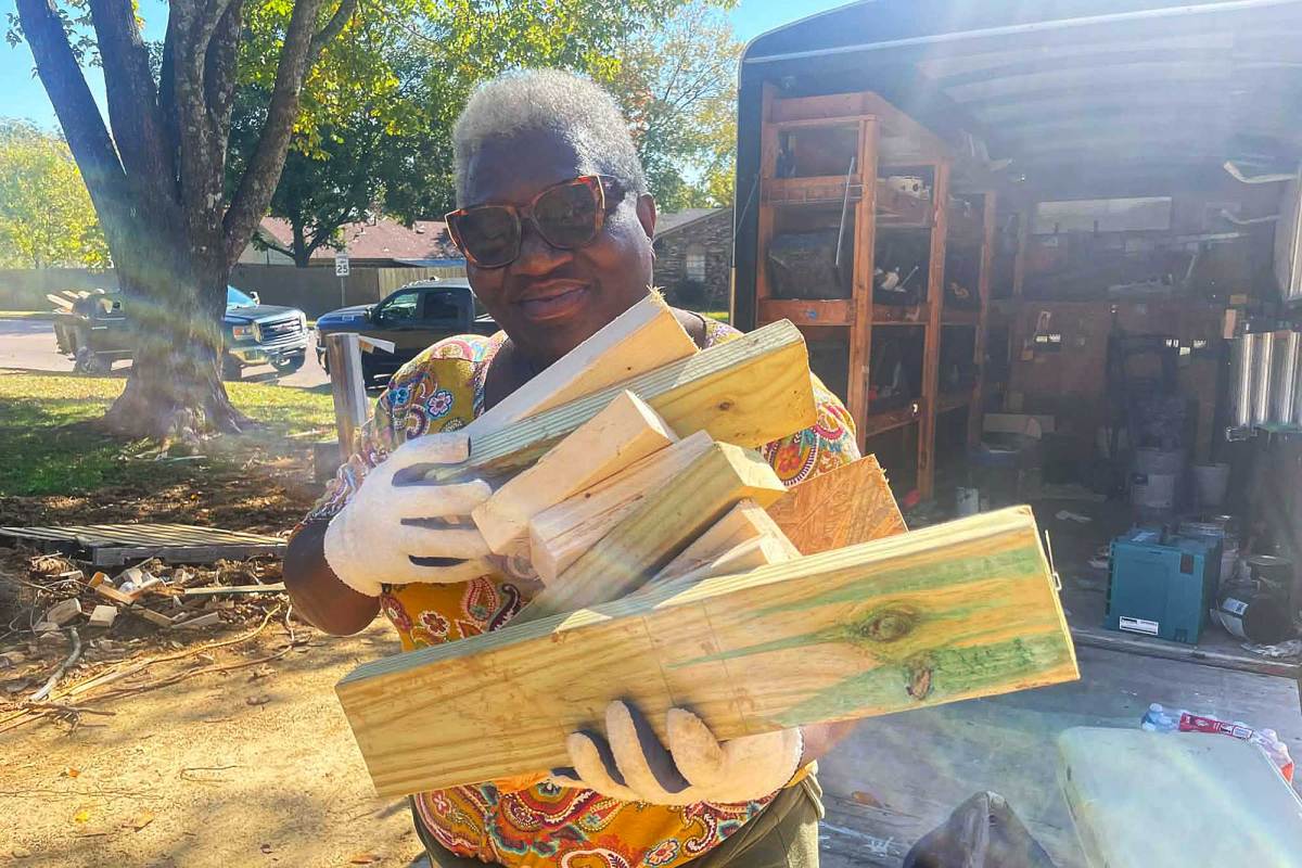 A woman holds cut blocks of wood in gloved hands