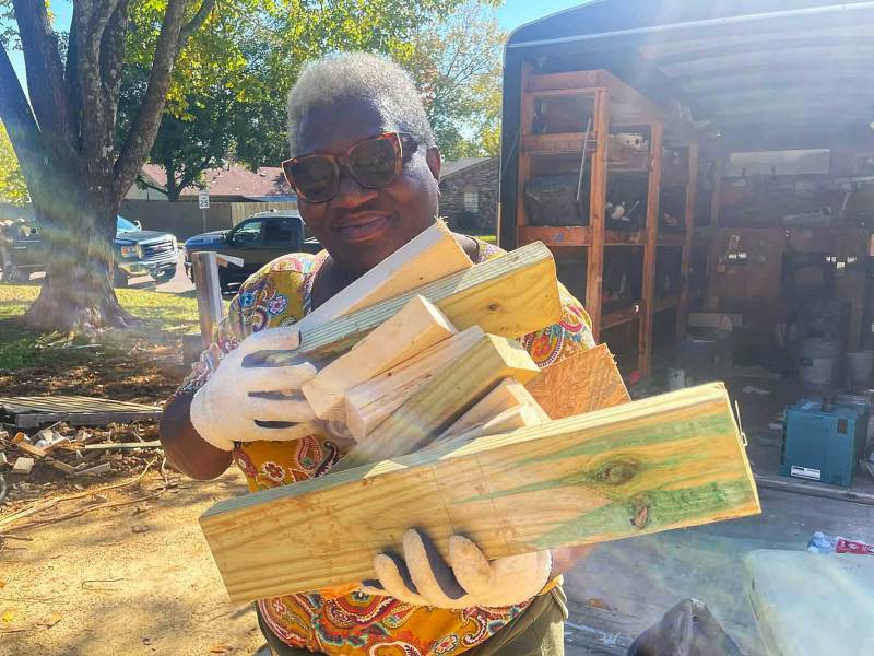 A woman holds cut blocks of wood in gloved hands