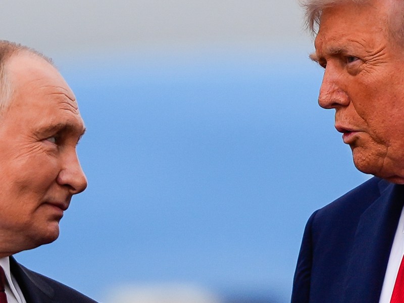 a photo of Putin smiling at Trump while trump speaks