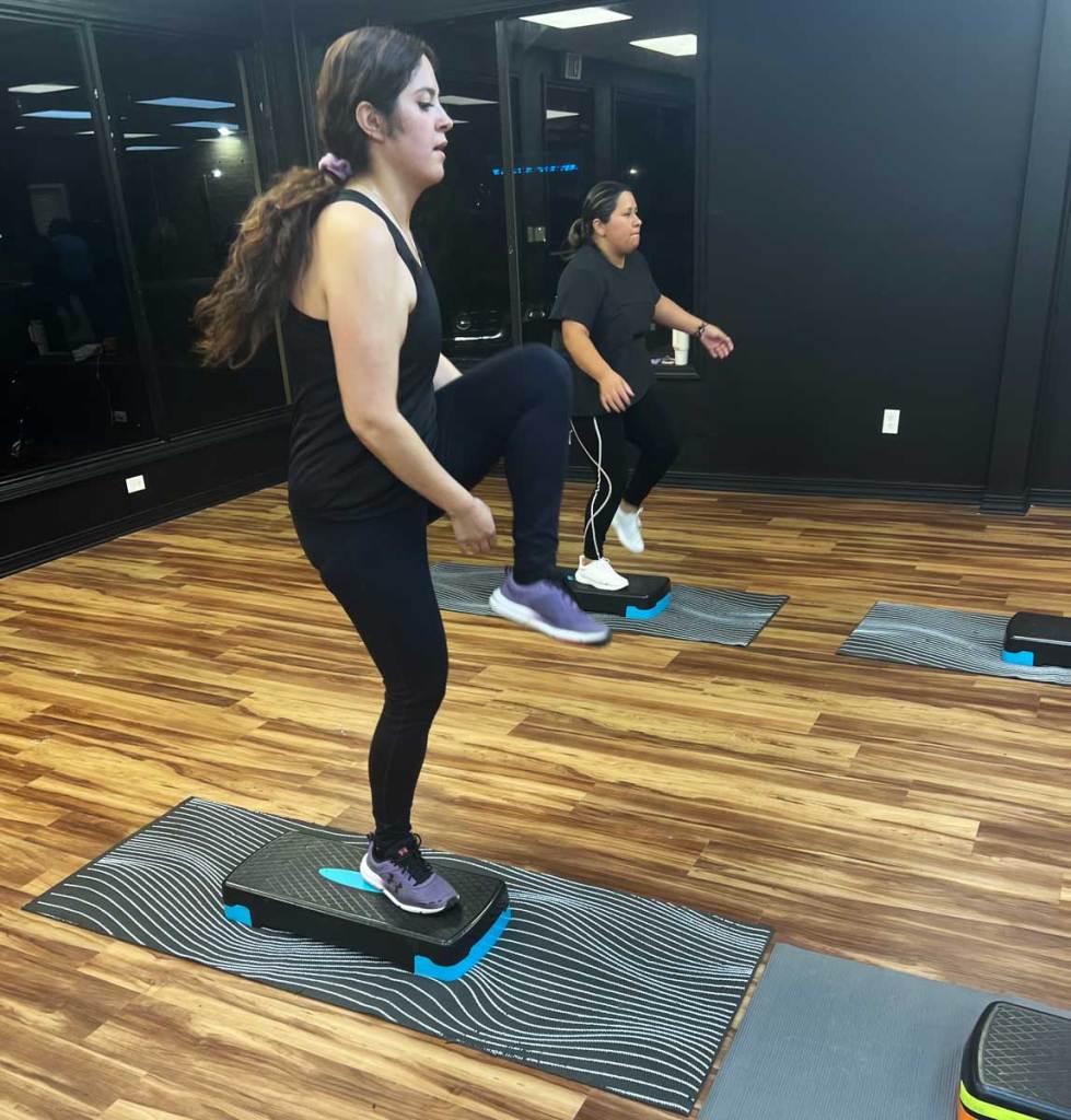 Two women do exercises on black platforms