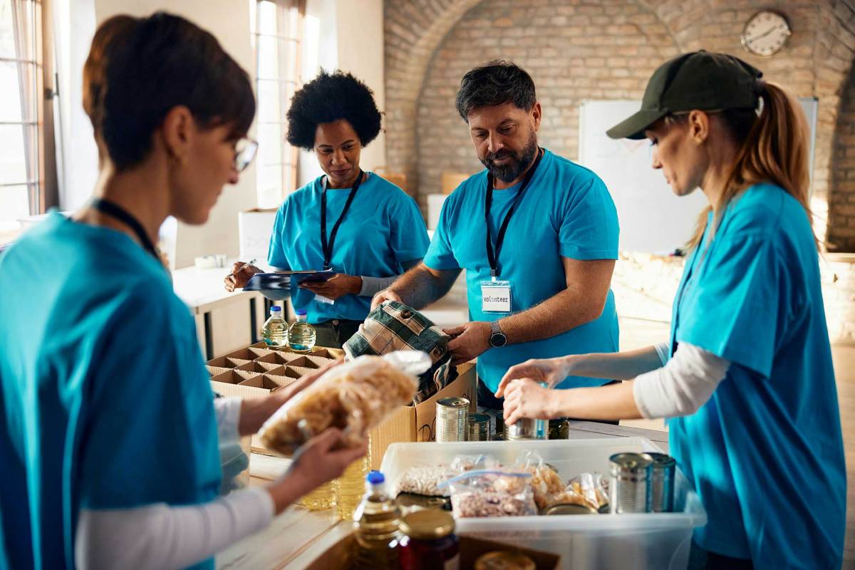 A diverse group of people in matching blue shirts sort through food donations for those in need