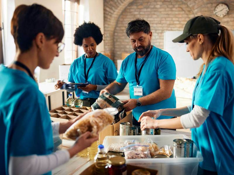 A diverse group of people in matching blue shirts sort through food donations for those in need