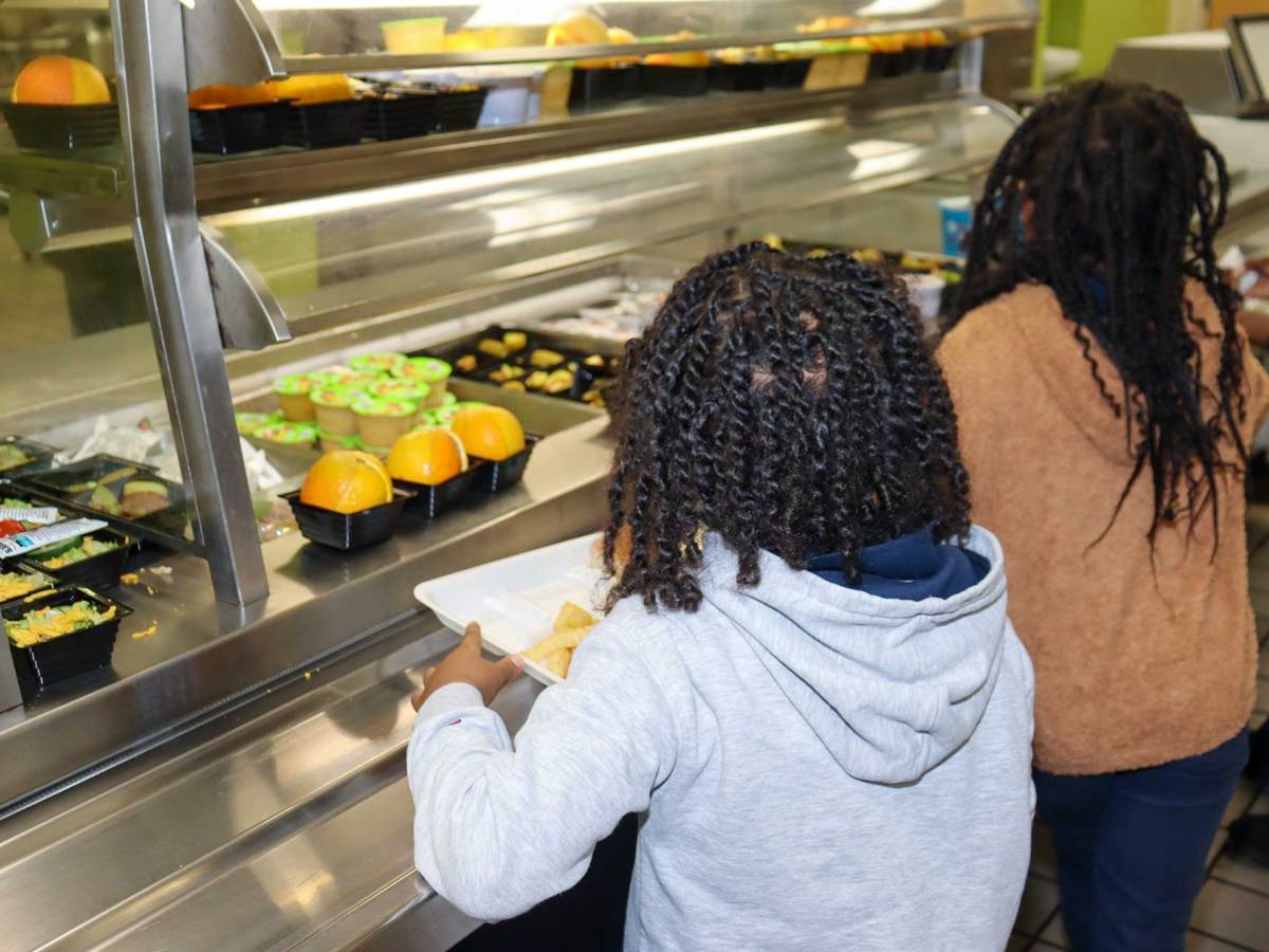 Two students go through the school cafeteria line, trays in hand