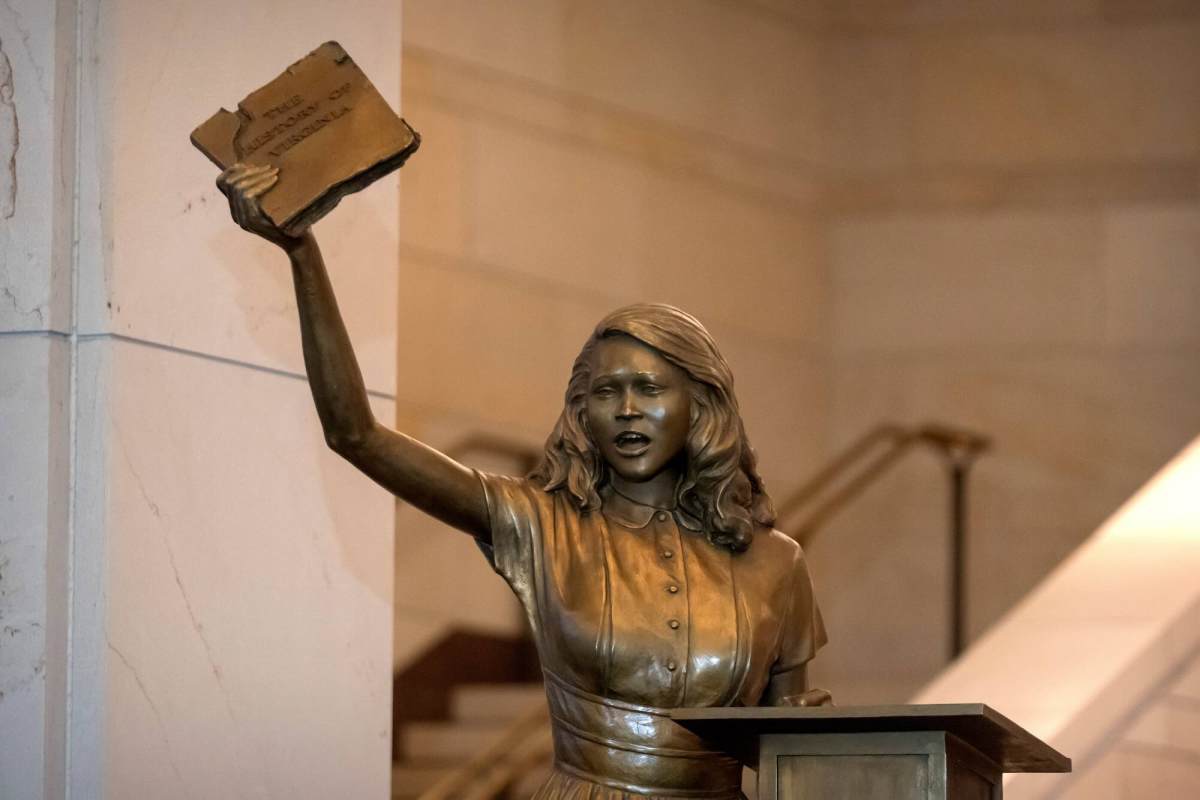 A bronze statue of Barbara Rose Johns posing with her hand in the air holding a book.