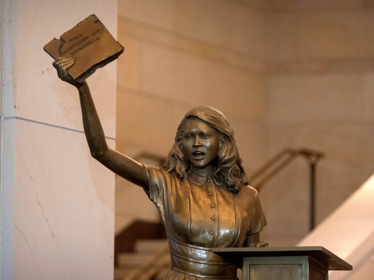 A bronze statue of Barbara Rose Johns posing with her hand in the air holding a book.