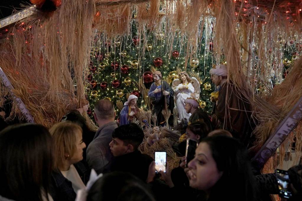 A crowd of people around three nativity statues on stage.