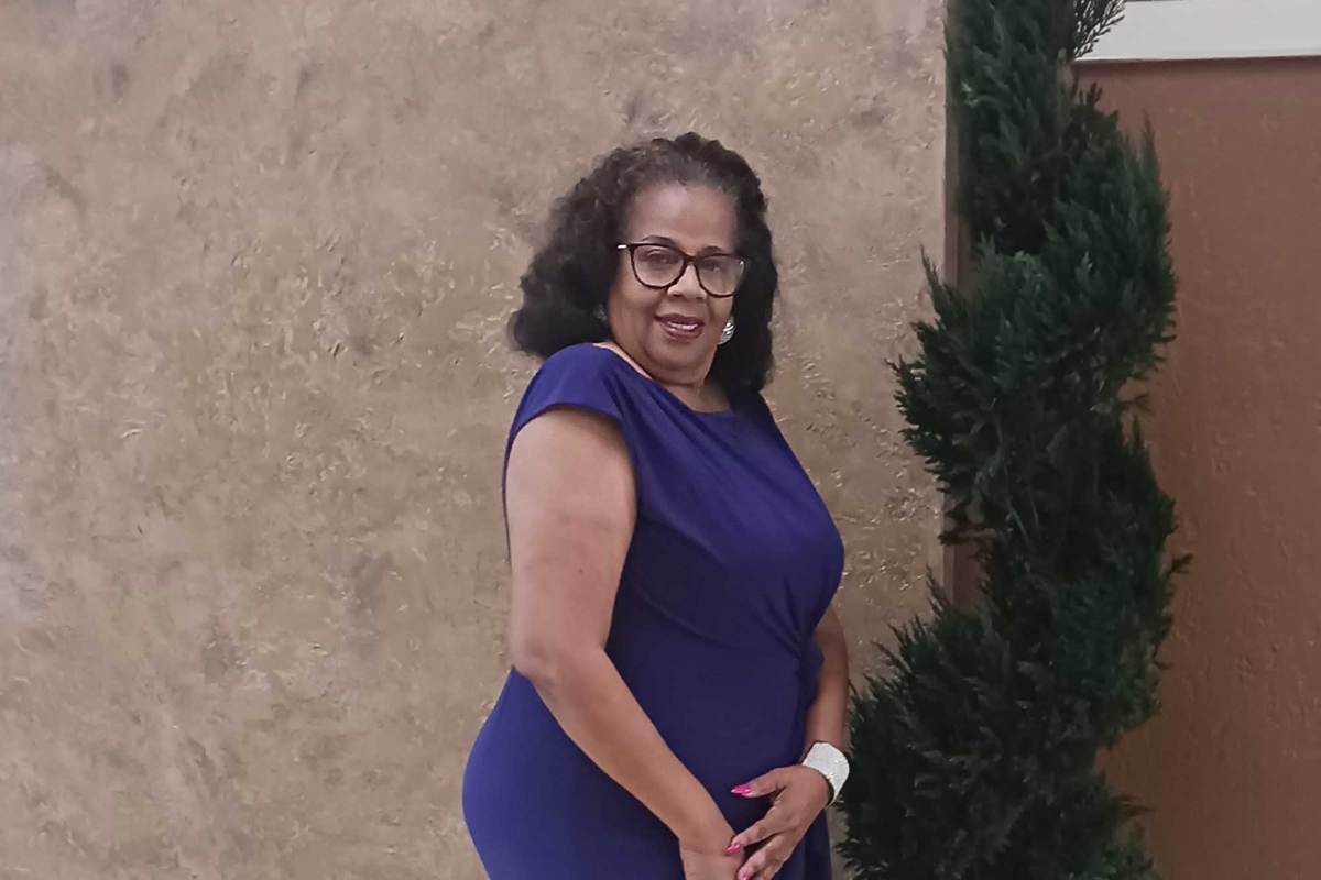 Bobbie Peoples standing outside of a building, wearing a blue dress