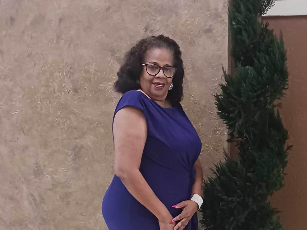 Bobbie Peoples standing outside of a building, wearing a blue dress