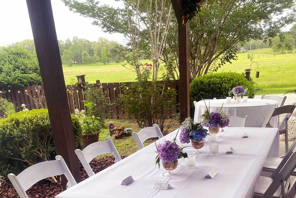 Tables set up for a wedding reception on a patio overlooking a green field