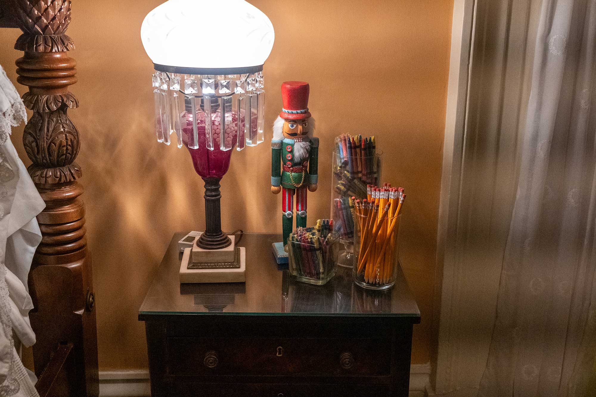 A nutcracker sits on a bedside table next to jars of pencils and crayons