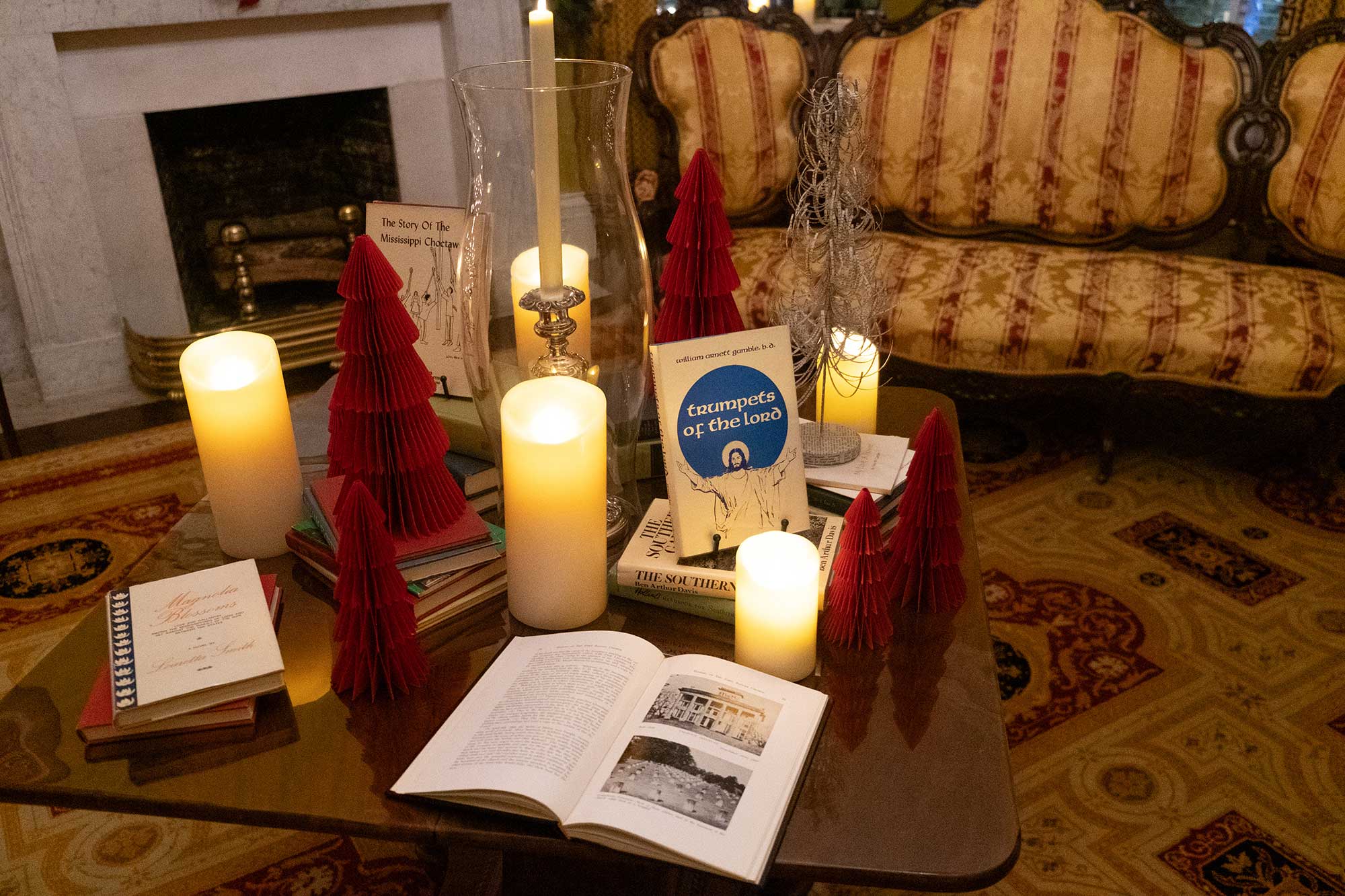 A table in the Governor's Mansion is covered in candles, red Christmas decorations and local Mississippi books