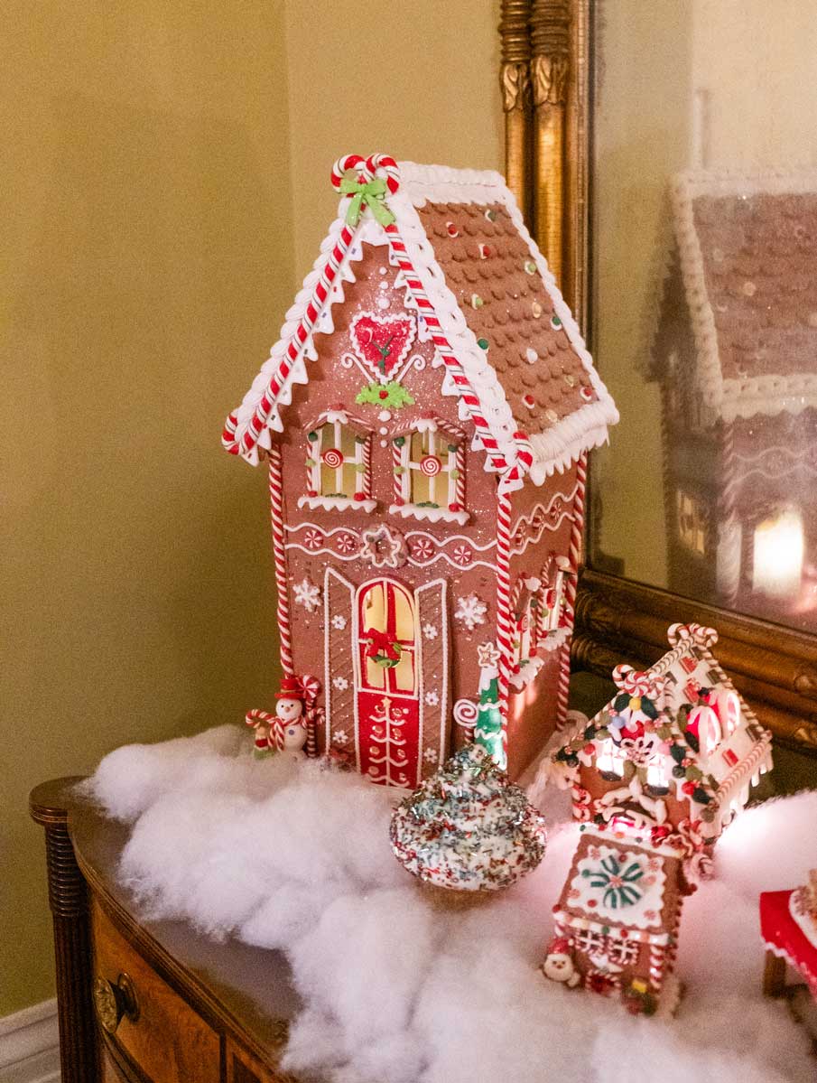 A Christmas scene made of gingerbread sits on a side table