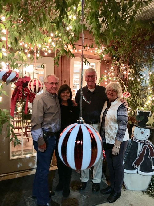 Four people pose together next to Christmas decorations