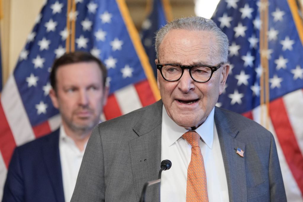 A close-up photo of Chuck Schumer speaking. Chris Murphy is in the background.