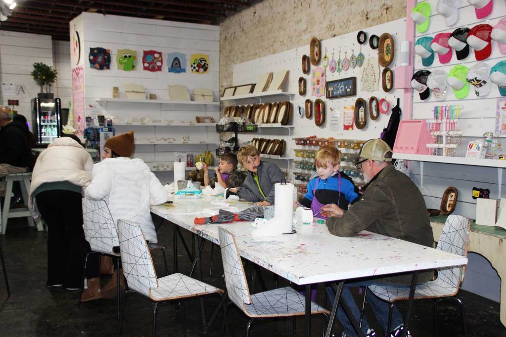 People sit at a table inside a business and paint crafts