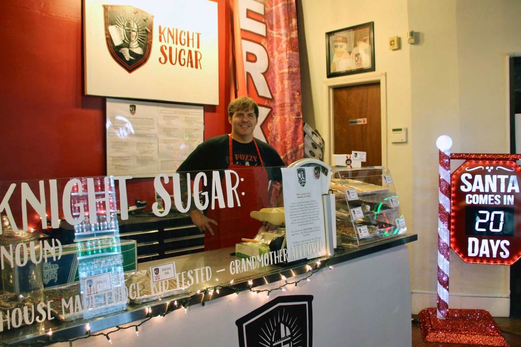 A person stands behind the counter at a sweet shop