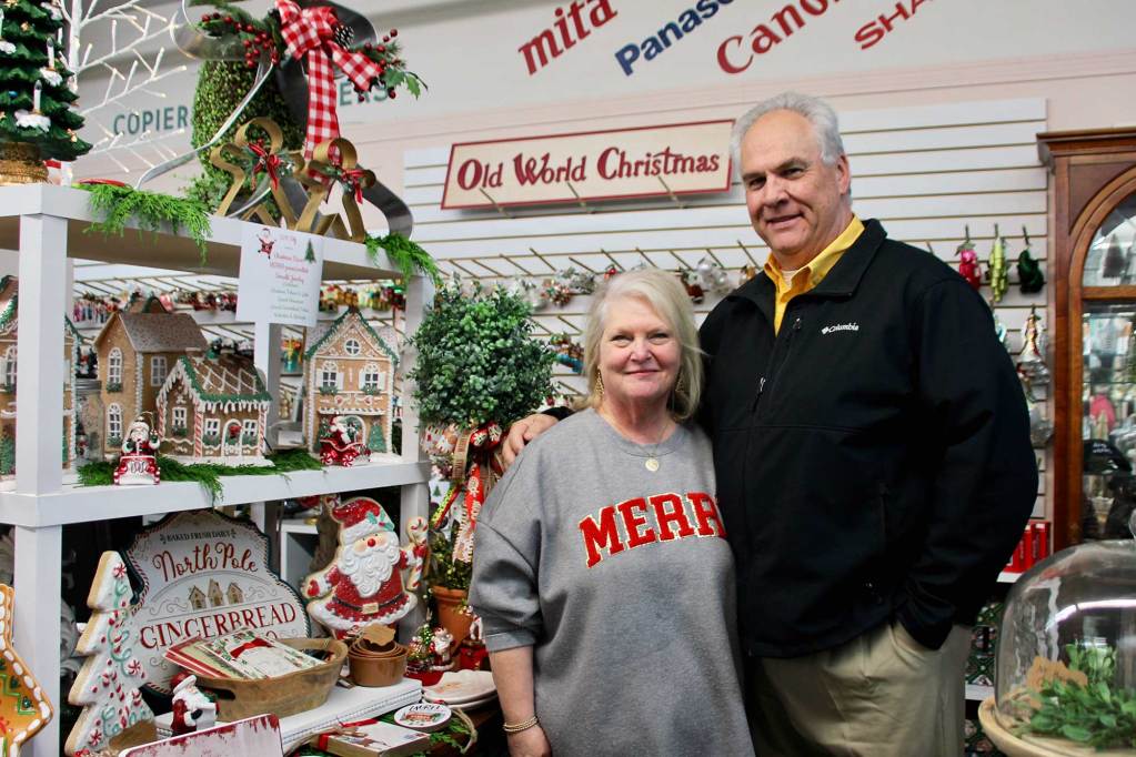 Two people stand together inside a retail shop filled with Christmas items