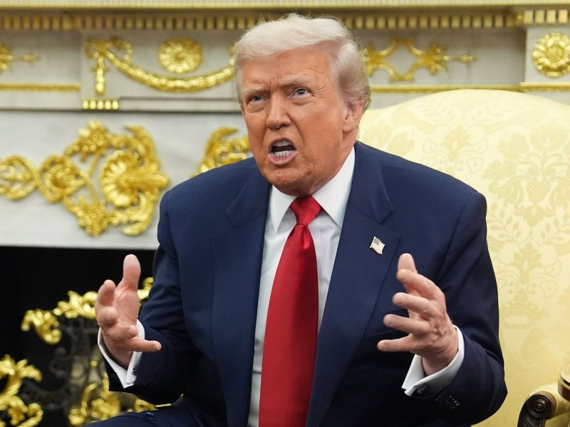 Trump sitting in a room covered in gold holding his hands up and looking frustrated.