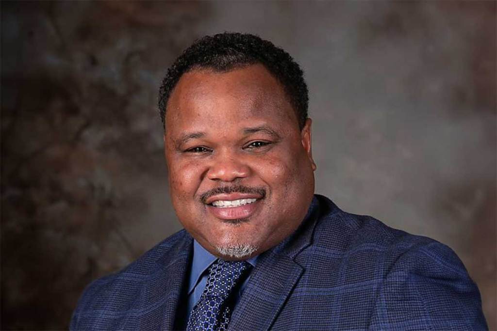 An official photo of Dr. Paul Morton, wearing a blue suit