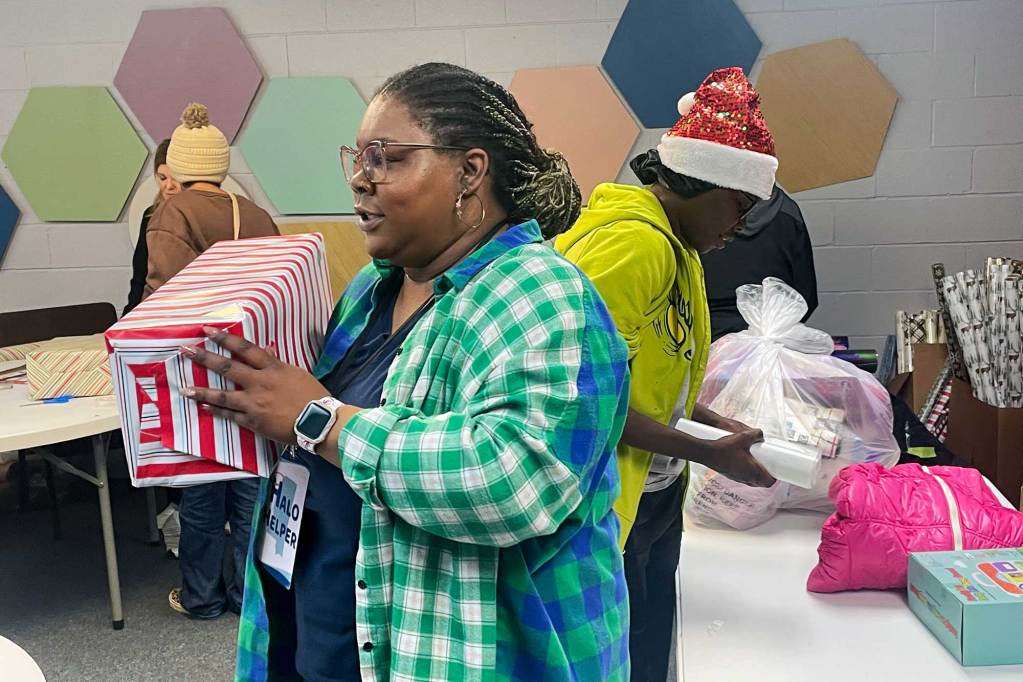 A busy room of people wrapping christmas gifts