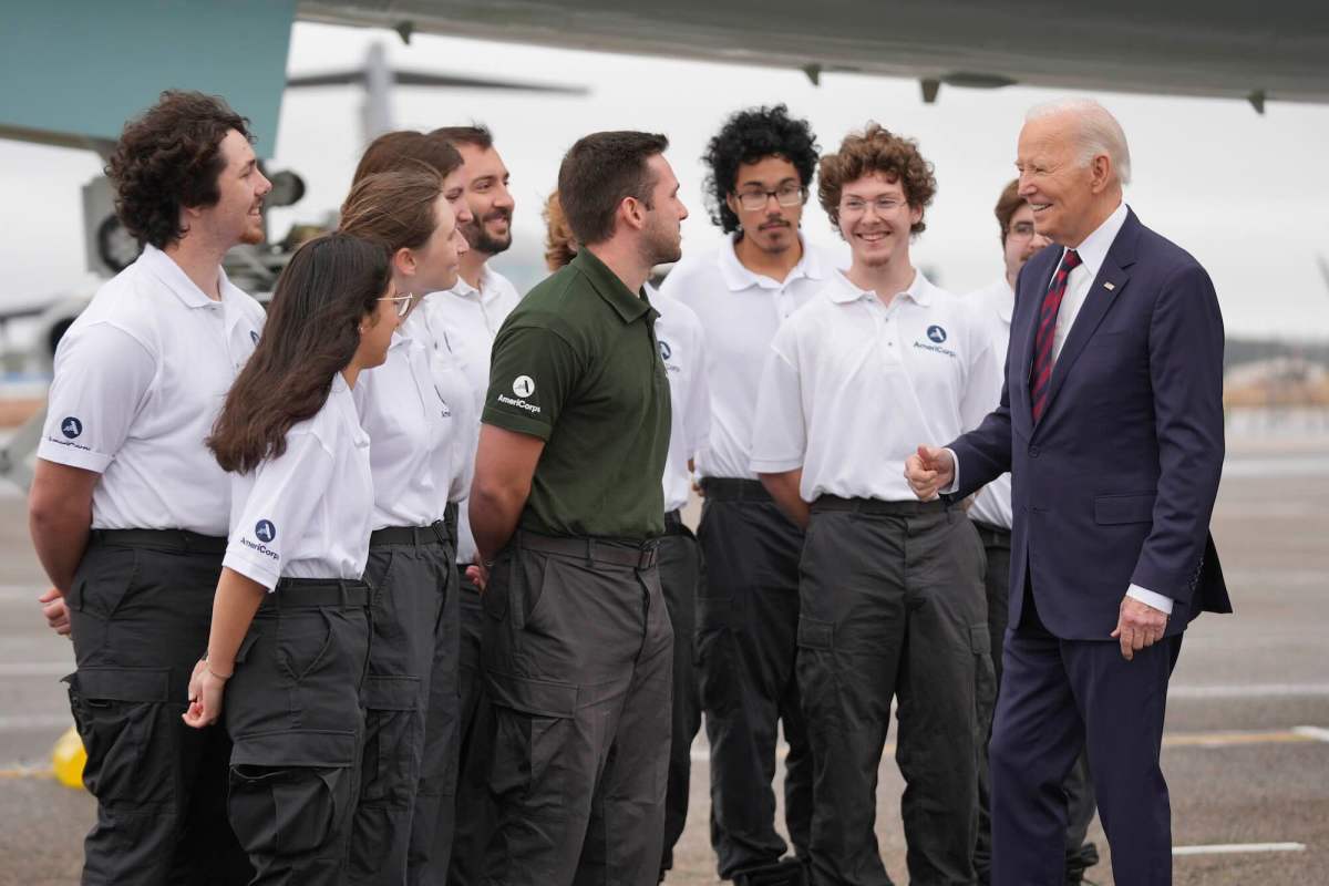 President Joe Biden greeting several young people. One is in a dark green shirt and the rest are wearing white shirts.