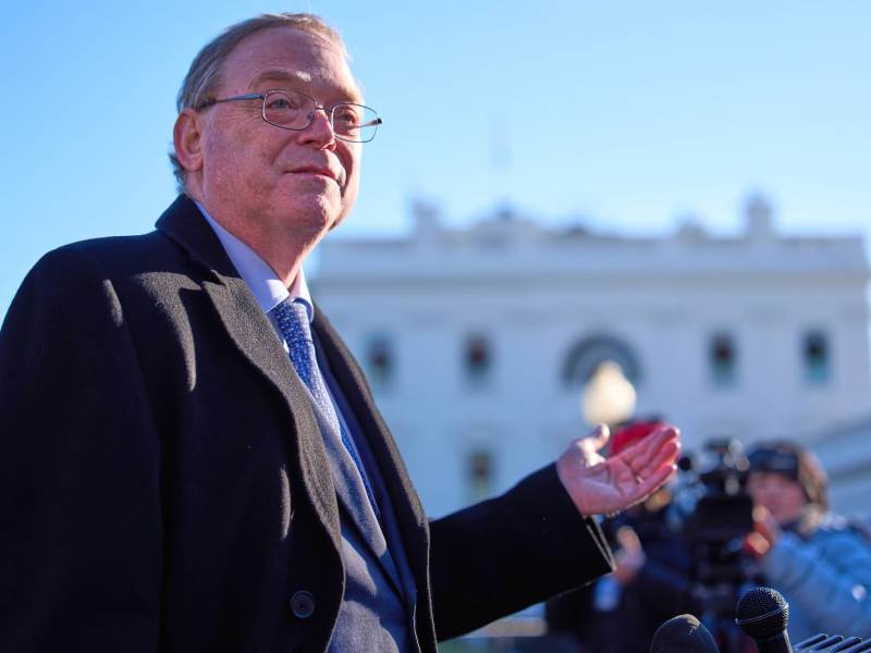 A man wearing glasses and a suit jacket speaking outside the White House